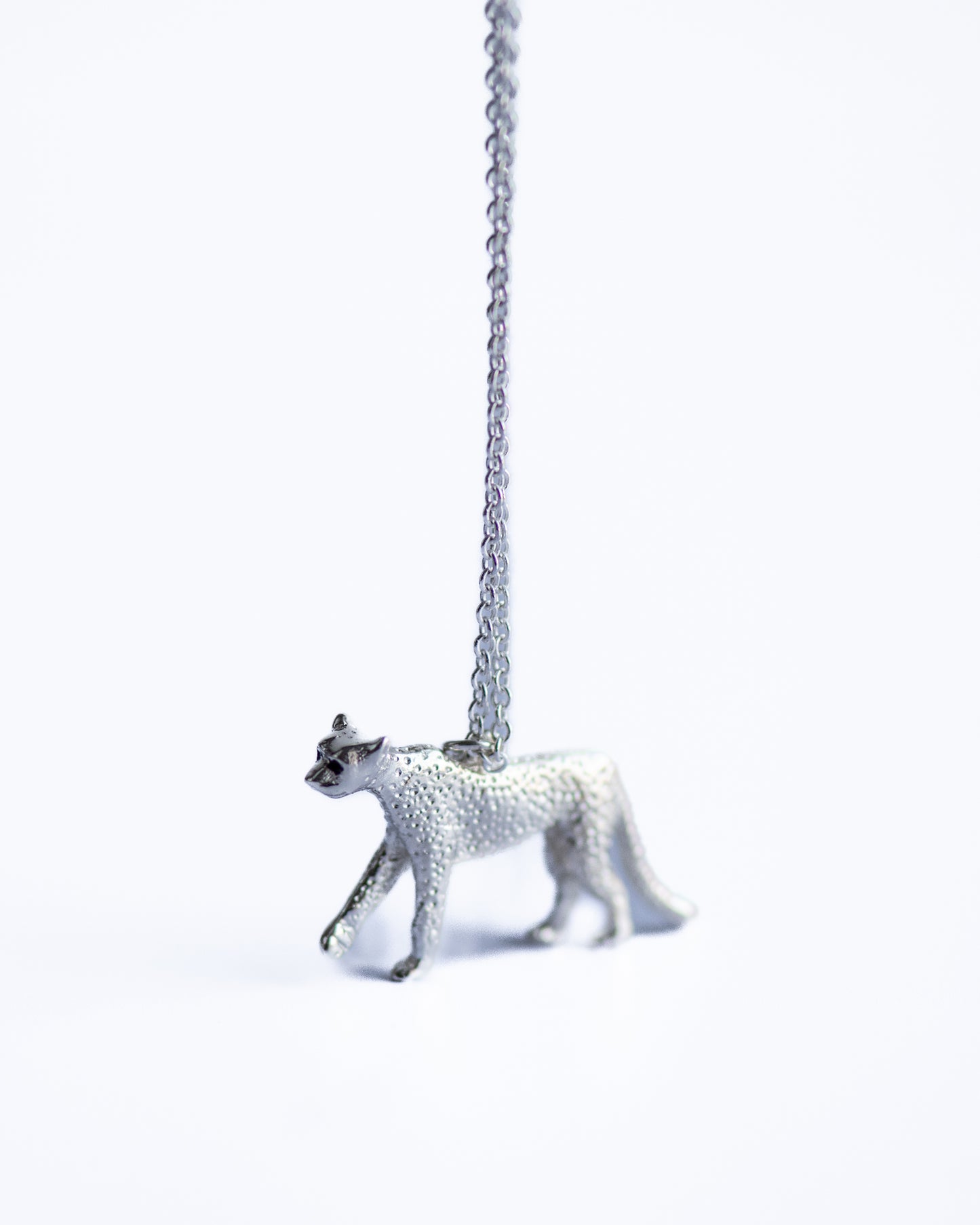 Silver panther pendant on a chain against a white background