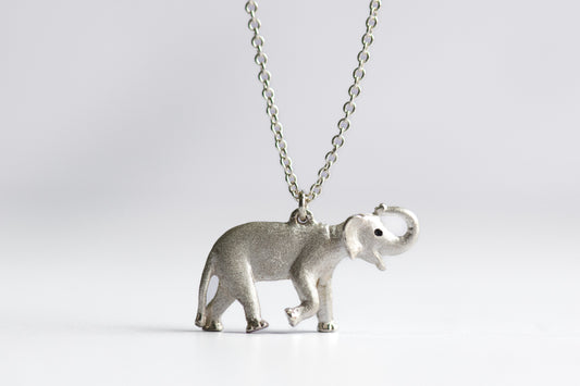 Silver elephant pendant on a chain against a light gray background