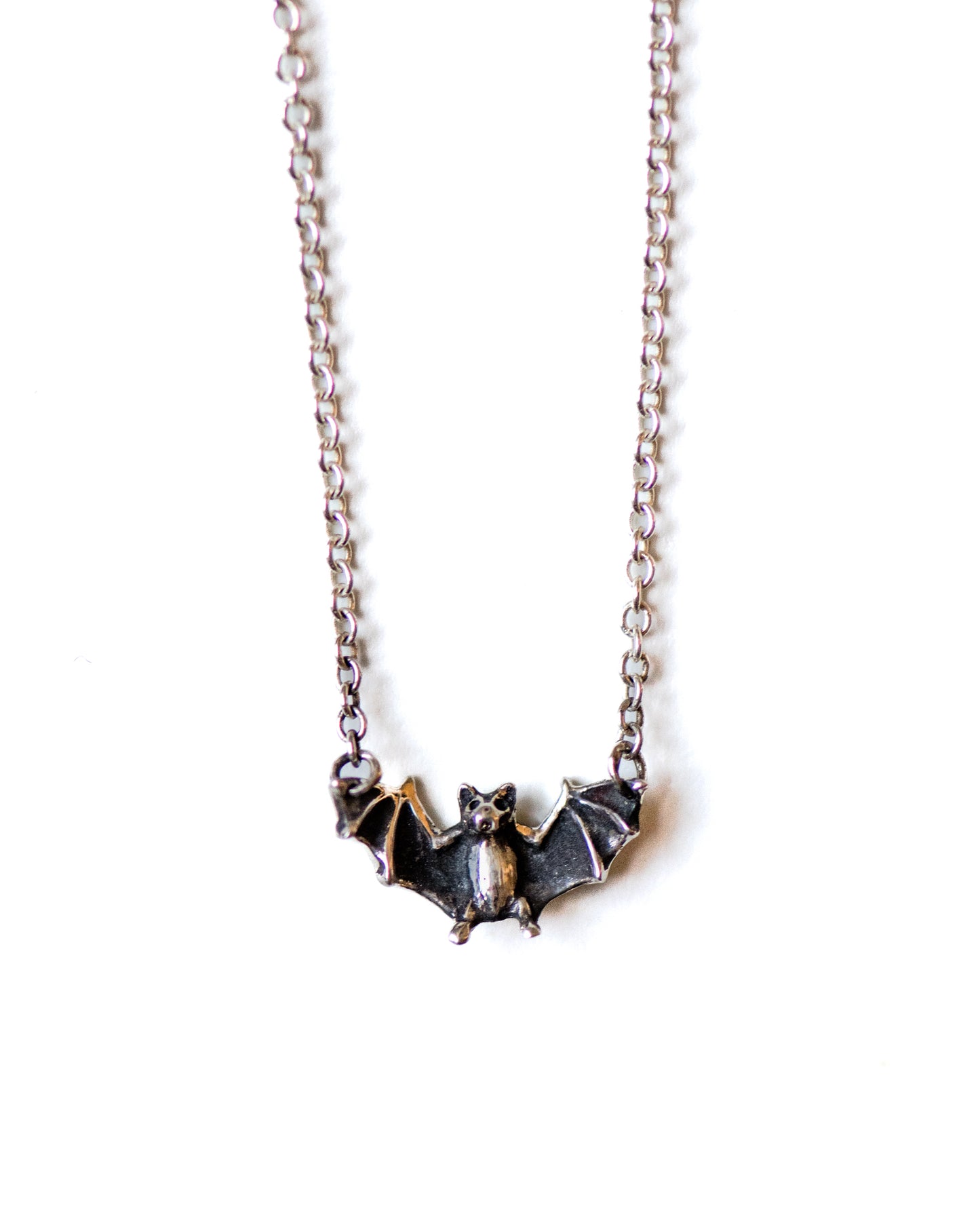 Silver bat-shaped pendant necklace on a white background