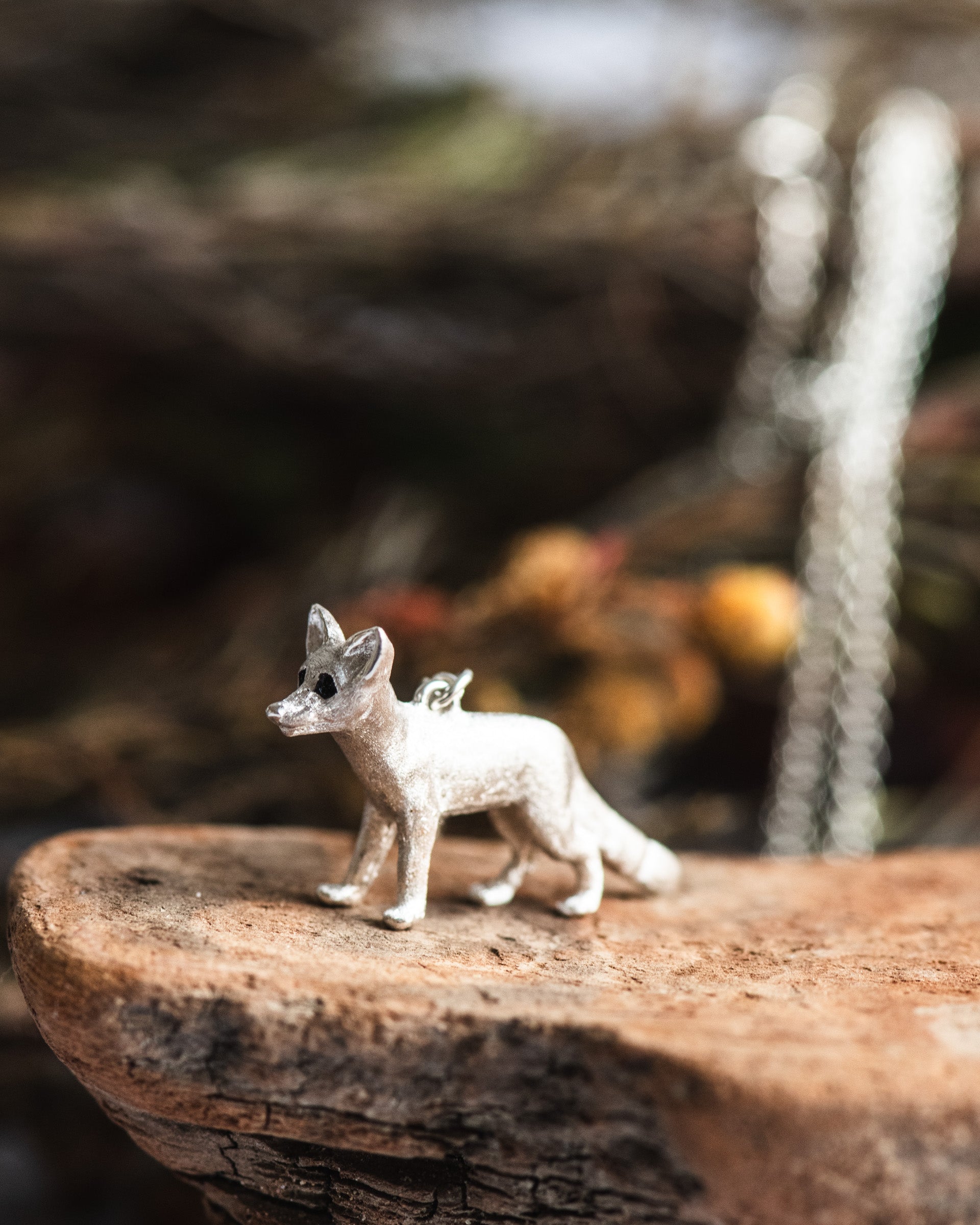 Small fox figurine on a wooden surface with a blurred natural background