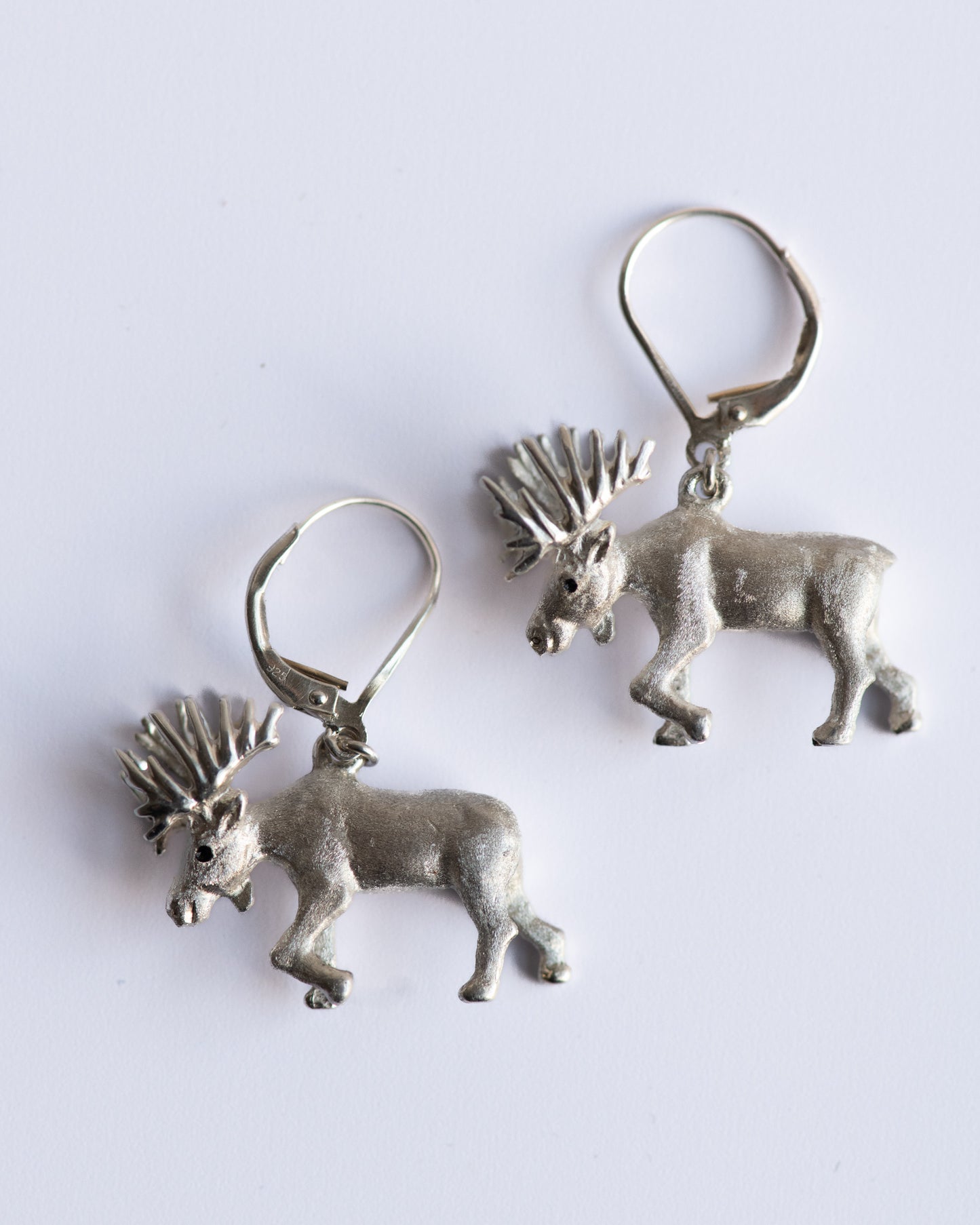 Pair of silver antelope-shaped earrings on a white background