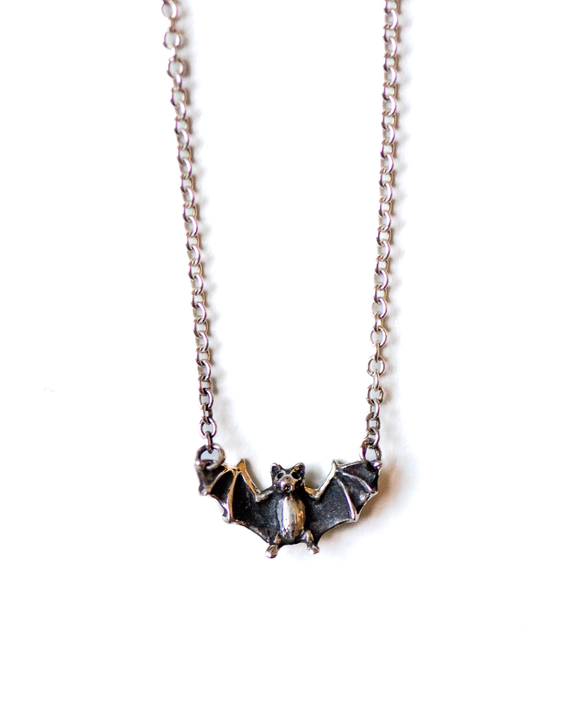 Silver bat-shaped pendant necklace on a white background