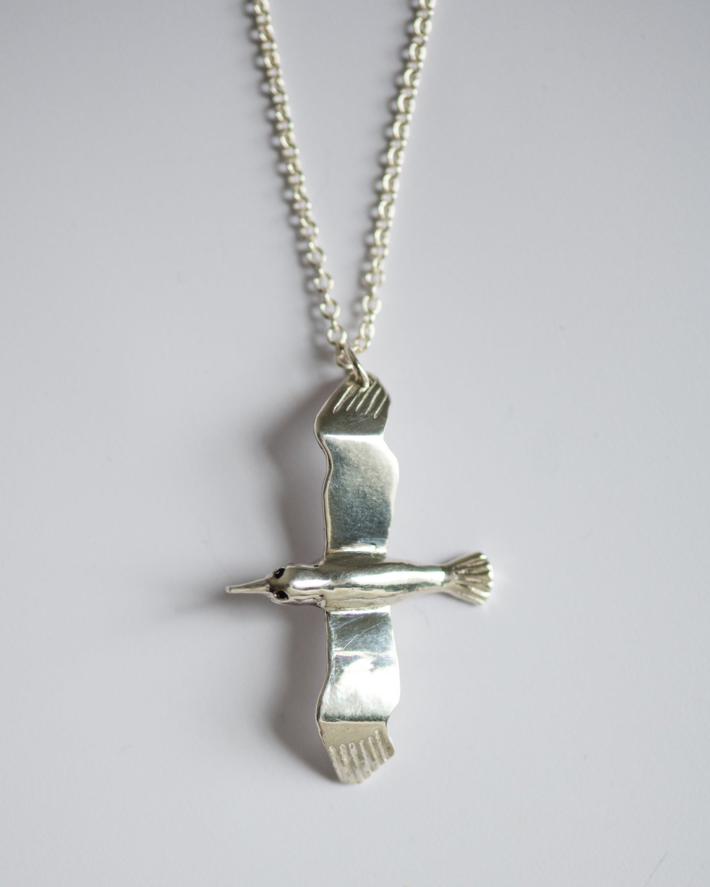 Silver Albatross bird pendant on a chain against a light gray background