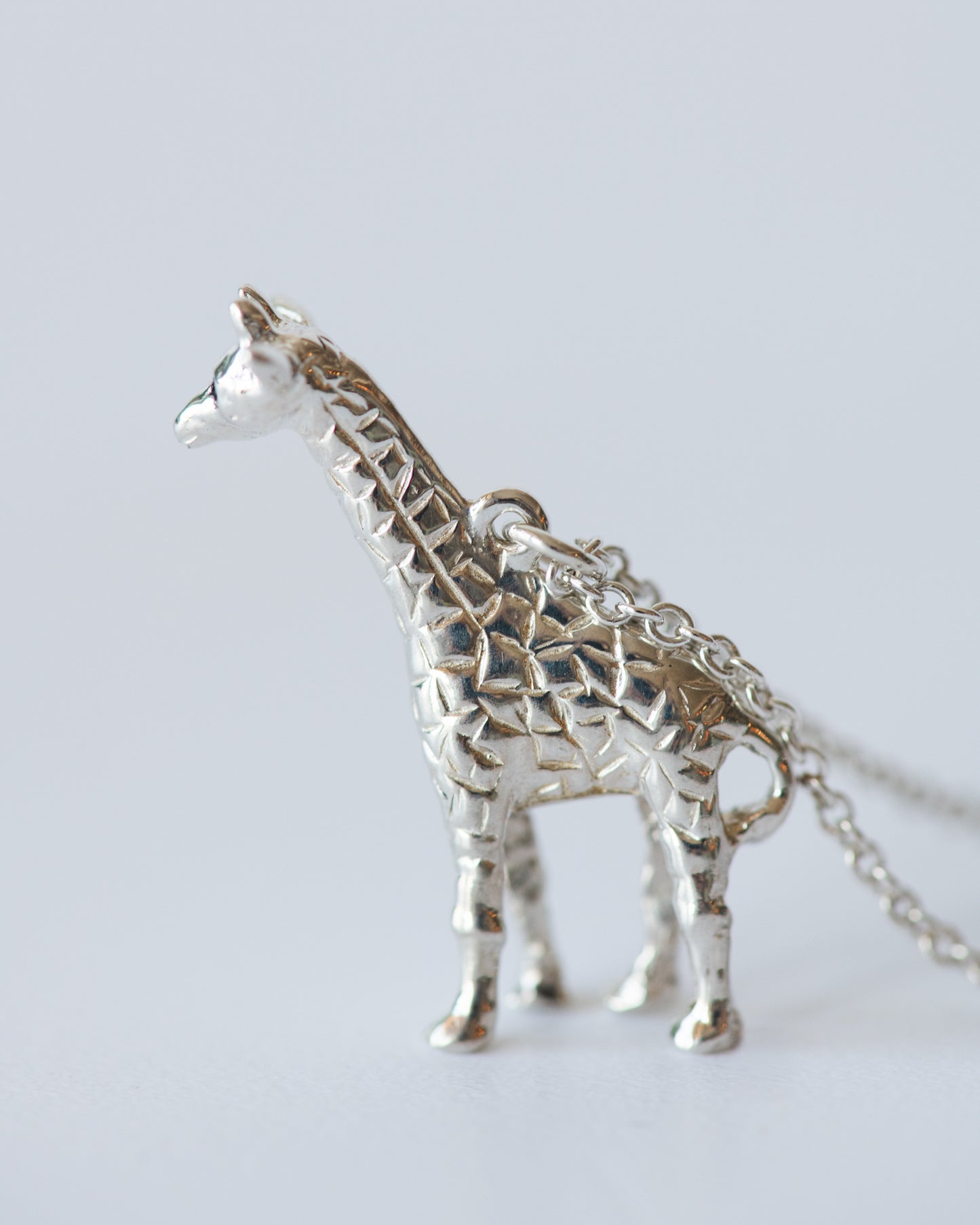Silver giraffe necklace on a light gray background
