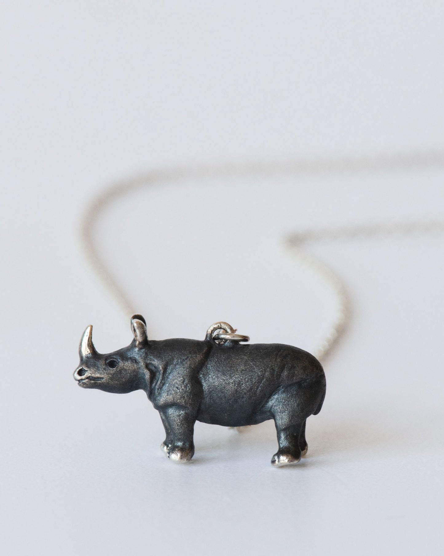 Sterling silver rhinoceros pendant on a chain against a white background