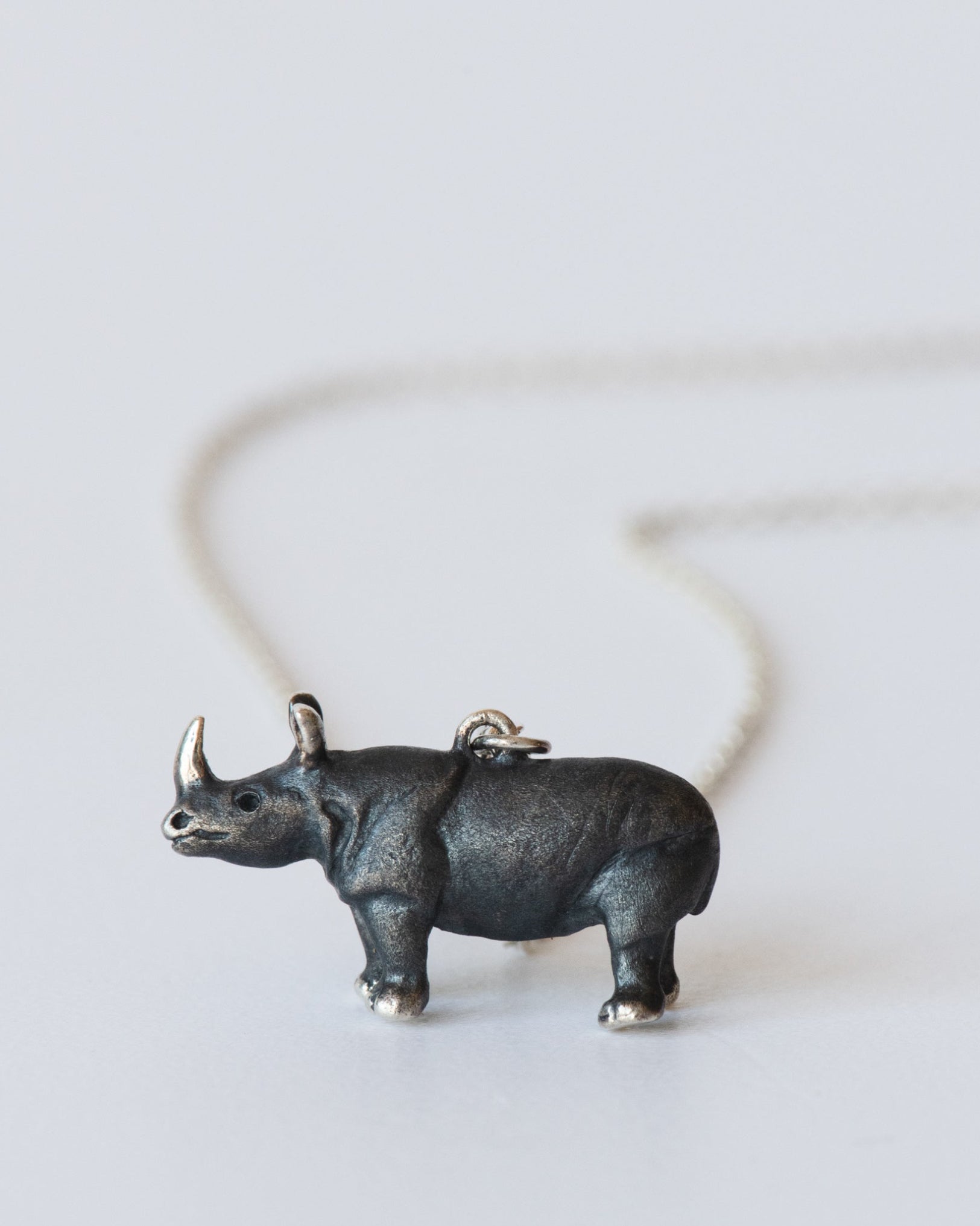 Sterling silver rhinoceros pendant on a chain against a white background