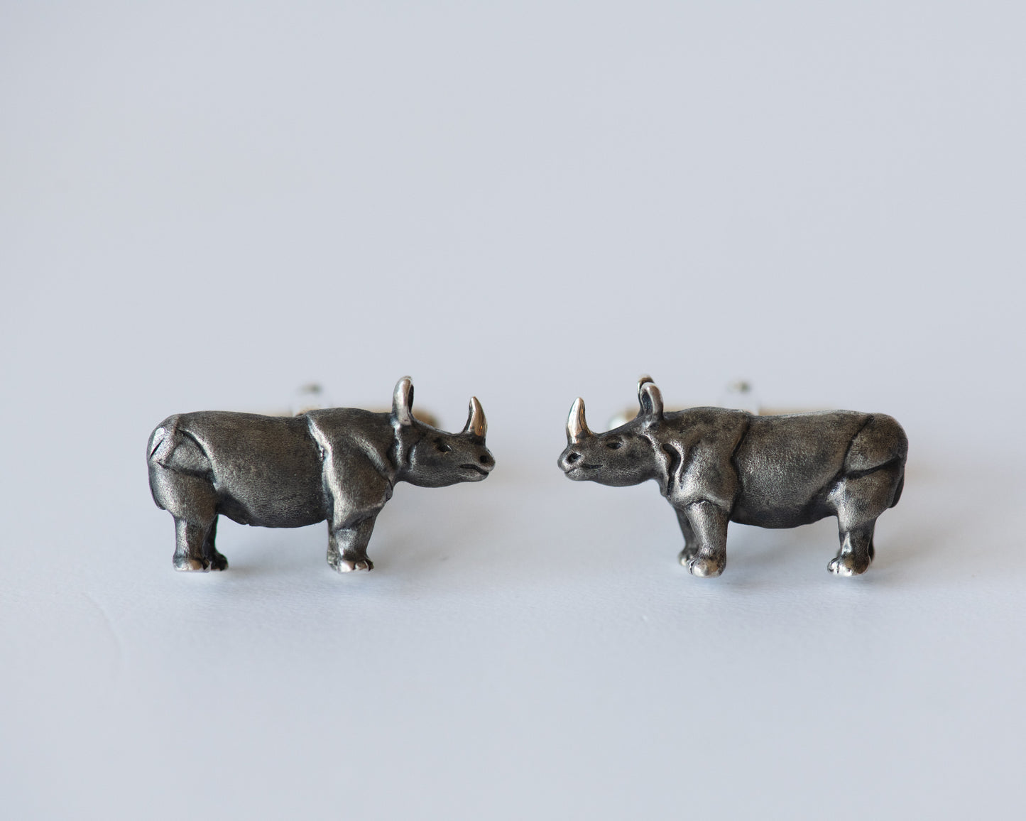 Pair of silver rhinoceros earrings on a light gray background