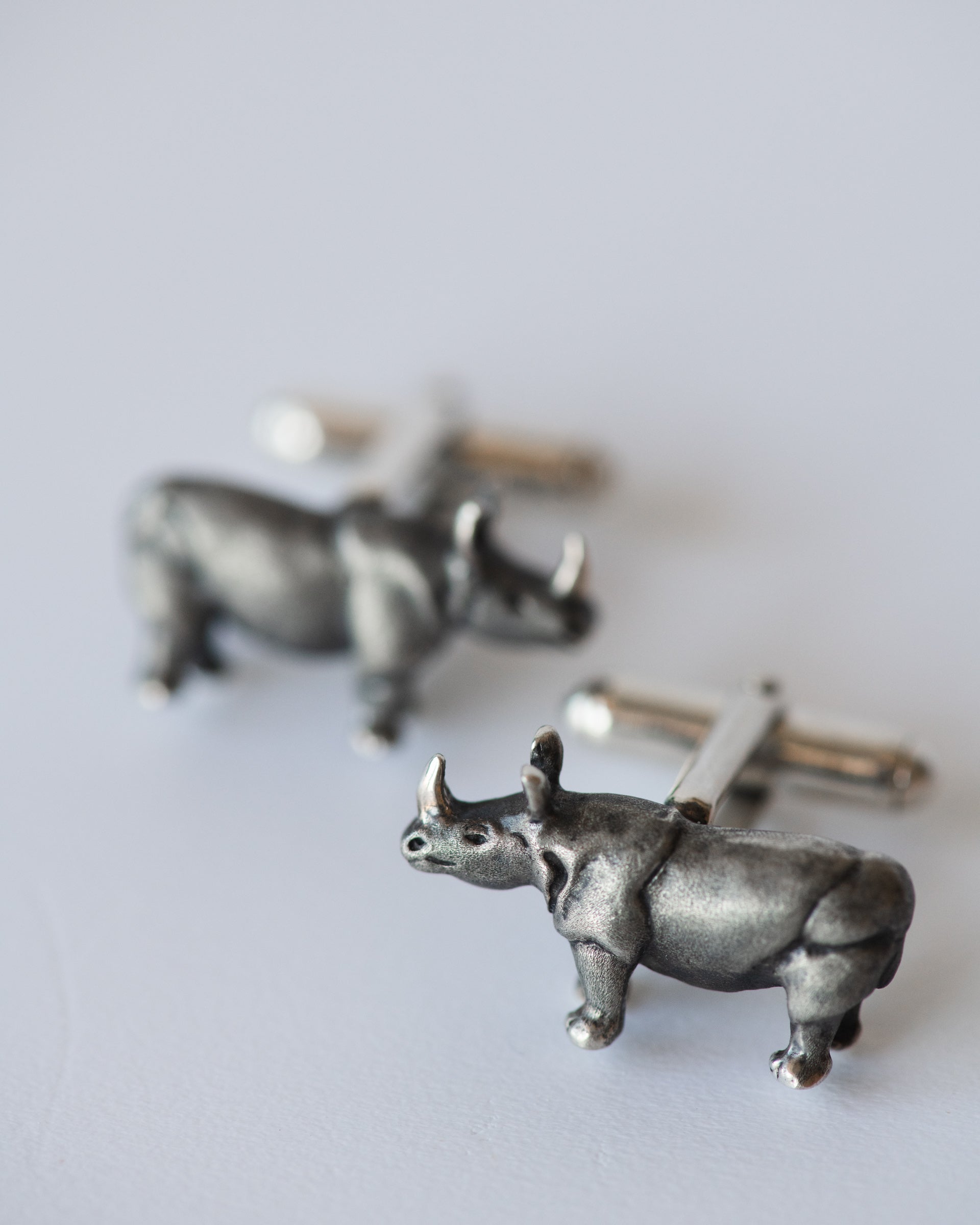 Silver rhinoceros cufflinks on a light gray background