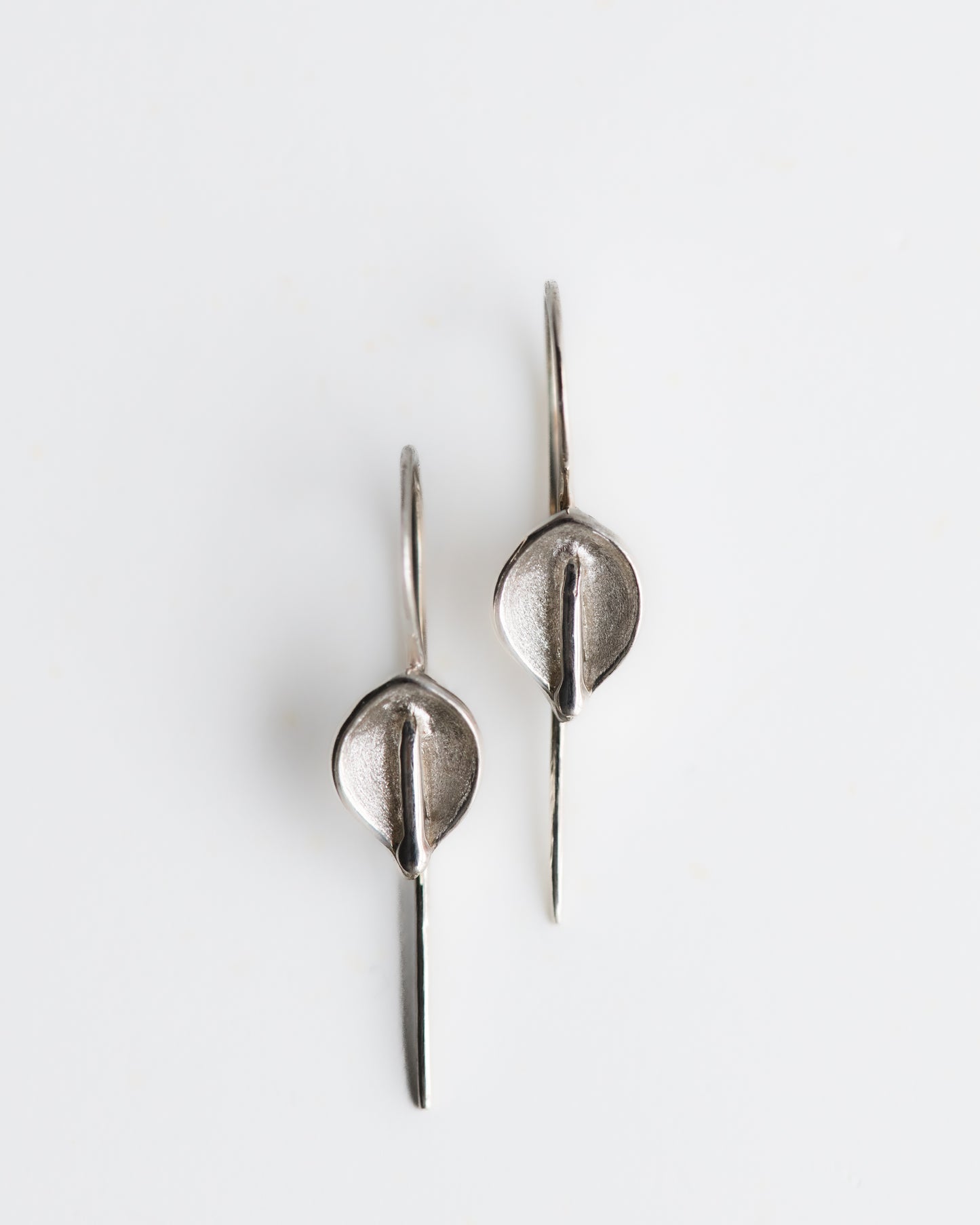Hand carved calla lily silver earrings on a white background