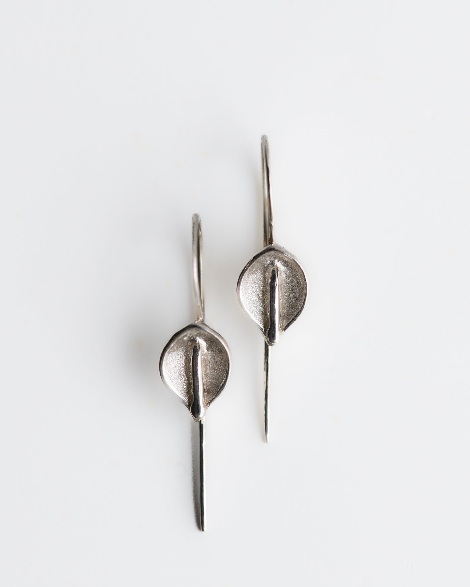 Hand carved calla lily silver earrings on a white background