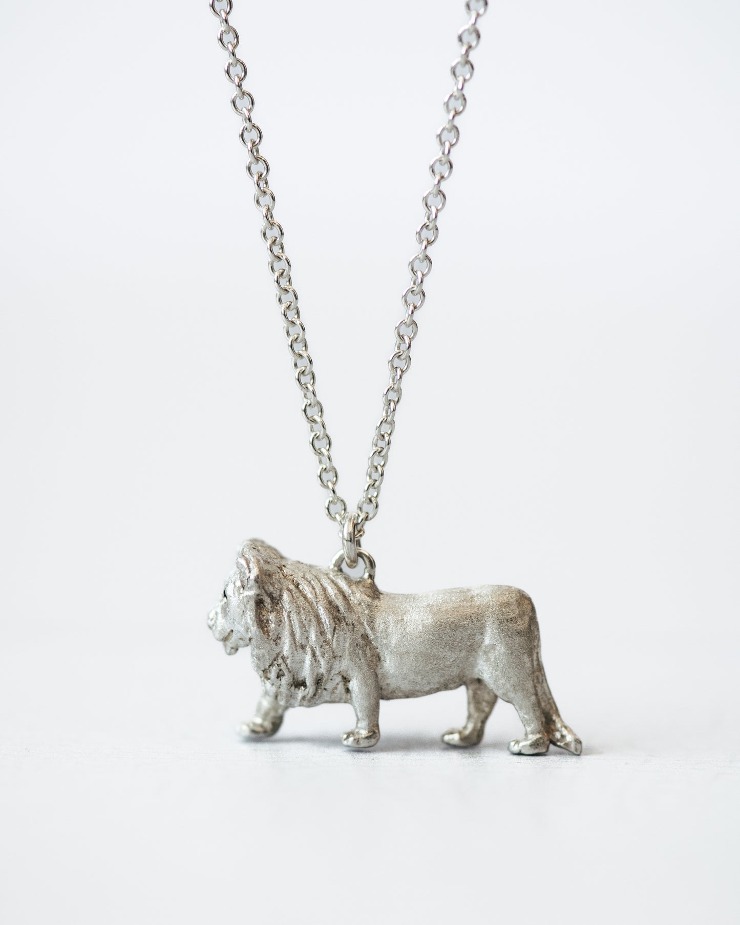 Silver lion pendant on a chain against a white background