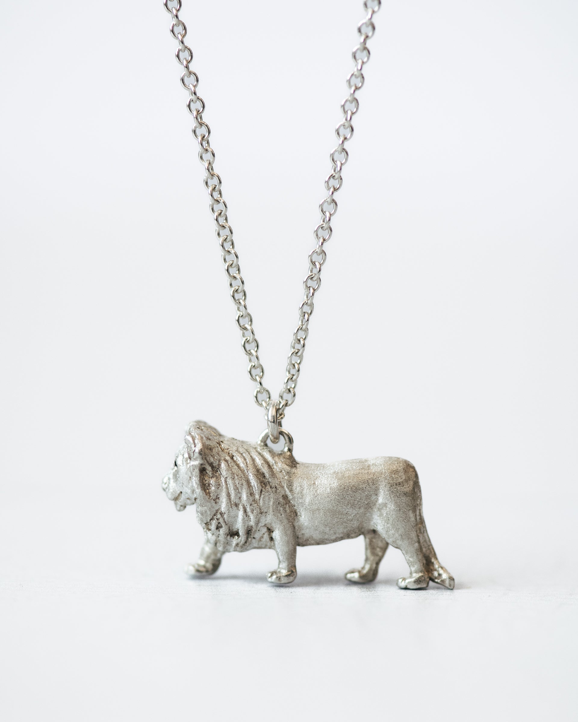 Silver lion pendant on a chain against a white background