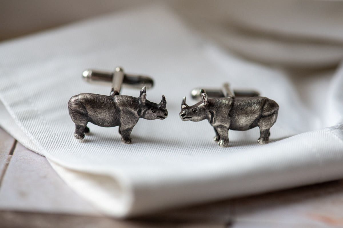 Silver rhinoceros cufflinks on a light gray background
